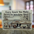 Cream aluminum sign with eight illustrated dogs peeking over a counter beneath a kitchen scene with cookies, reading “Every snack you make, I’ll be watching you.”