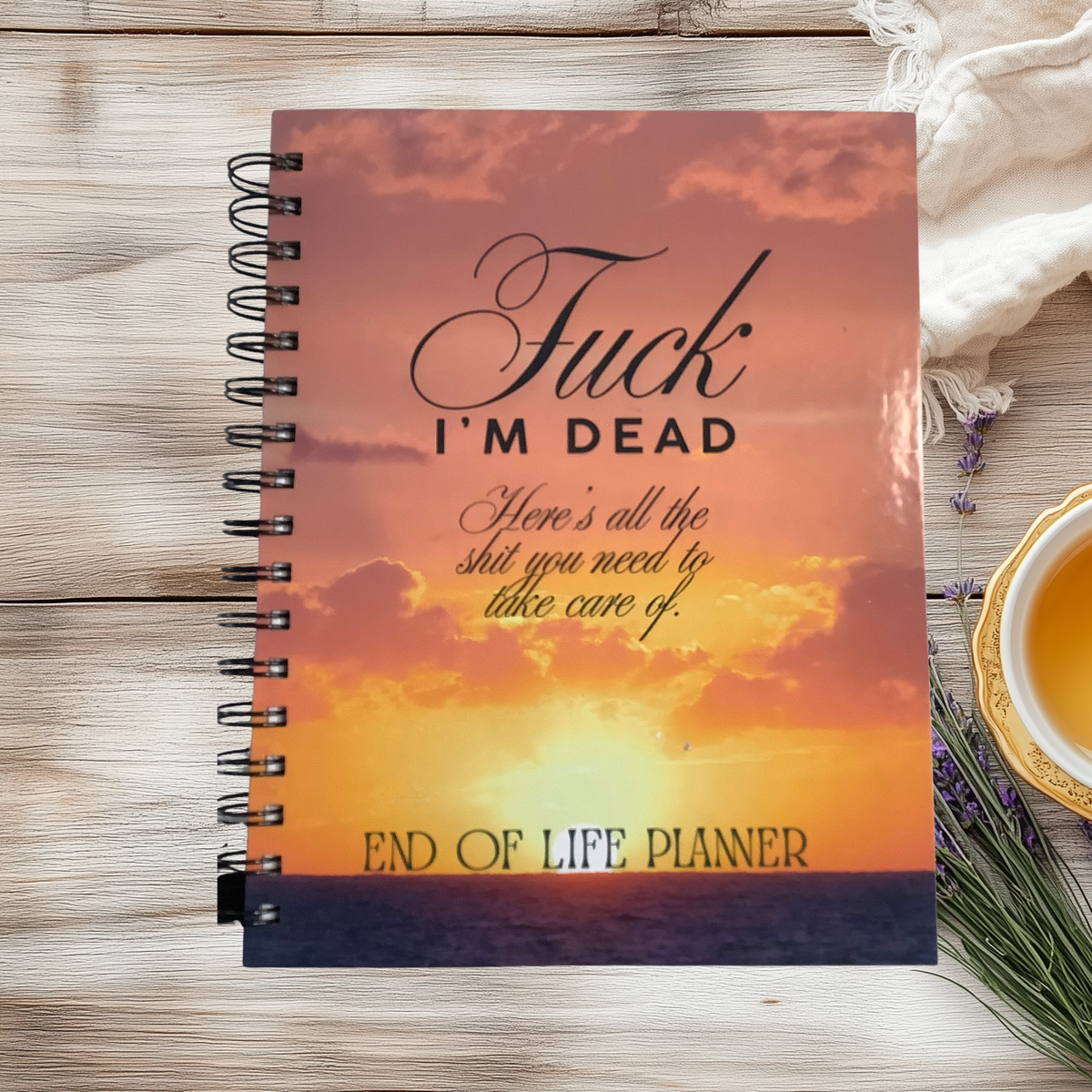 Spiral-bound end-of-life planner with an orange sunset cover reading “Fuck, I’m dead. Here’s all the shit you need to take care of.”
