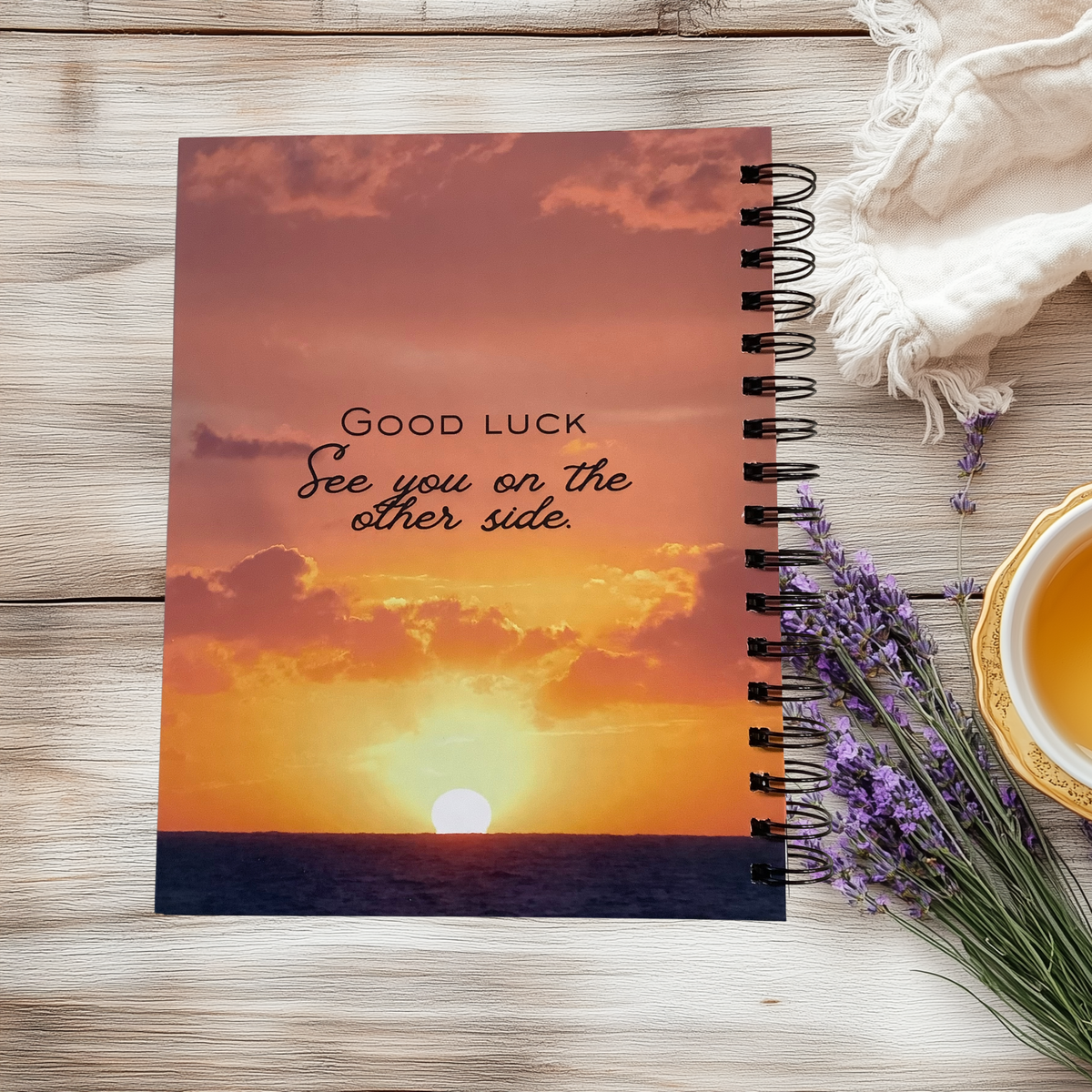 Back cover of a spiral-bound planner with an orange sunset over water, reading “Good luck. See you on the other side.”