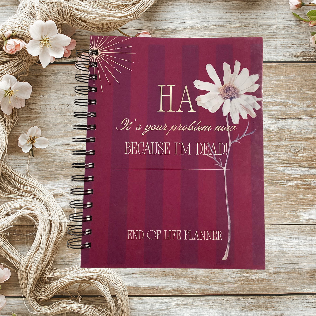 Spiral-bound end-of-life planner with a burgundy cover and white flower, reading “Ha, it’s your problem now because I’m dead!”