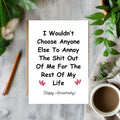 White rectangular card with pink hearts, reading “I wouldn’t choose anyone else to annoy the shit out of me for the rest of my life. Happy Anniversary!”