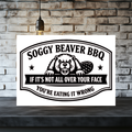 White aluminum sign with a black beaver illustration and two stars, reading “Soggy Beaver BBQ. If it’s not all over your face, you’re eating it wrong.”
