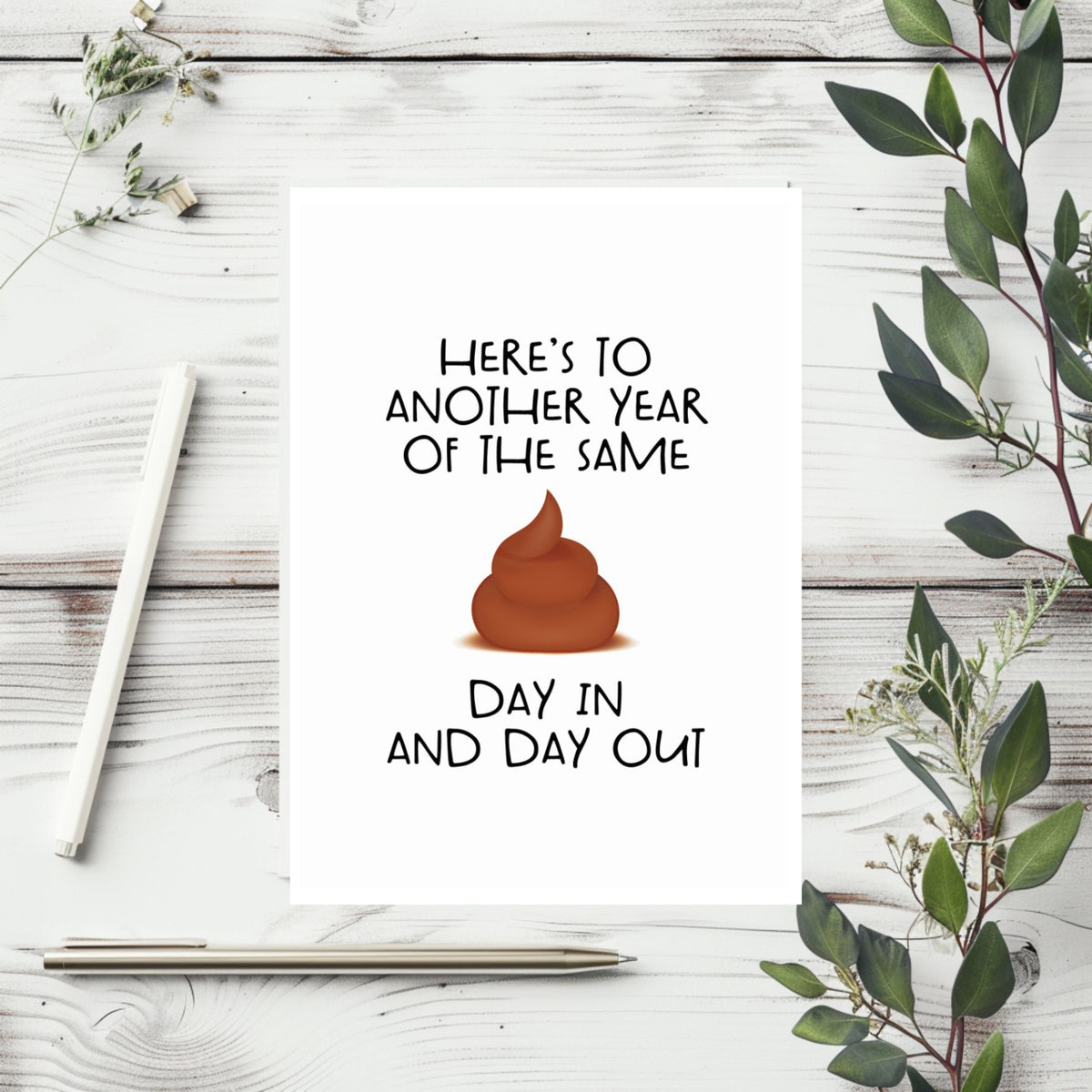 White rectangular card reading “Here’s to another year of the same,” with a poop illustration replacing “shit,” followed by “day in and day out.”