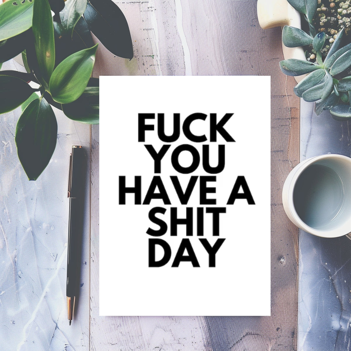 White rectangular greeting card with bold black lettering reading “Fuck you, have a shit day.”