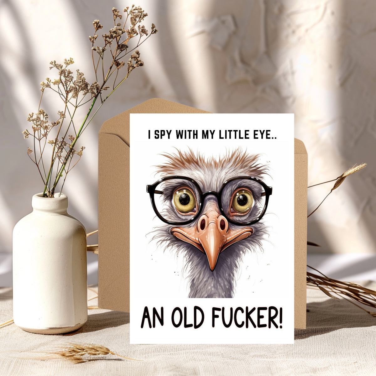 White rectangular card with a cartoon ostrich wearing black glasses, reading “I spy with my little eye... an old fucker!”