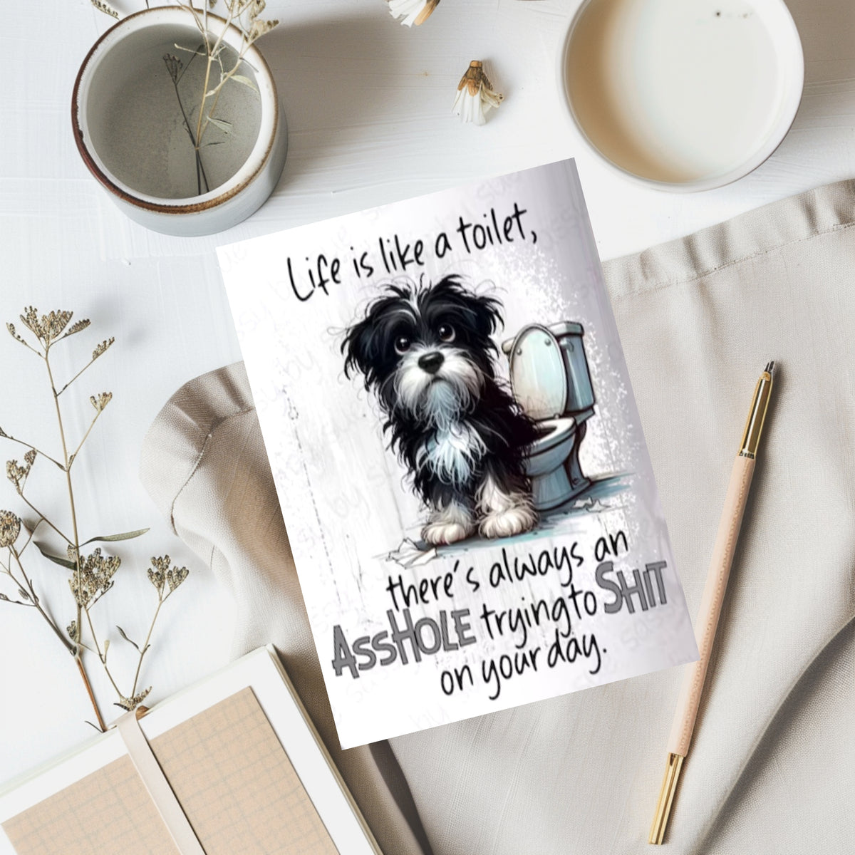 White rectangular card with a shaggy black-and-white dog beside a toilet, reading “Life is like a toilet, there’s always an asshole trying to shit on your day.”