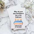 White rectangular wedding card with a wooden bed and blue bedding, reading “May all your up’s and down’s be in the bedroom” and “Congratulations on your wedding.”