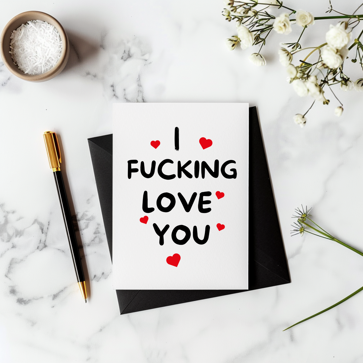 White rectangular greeting card with bold black lettering reading “I Fucking Love You,” surrounded by small red hearts.