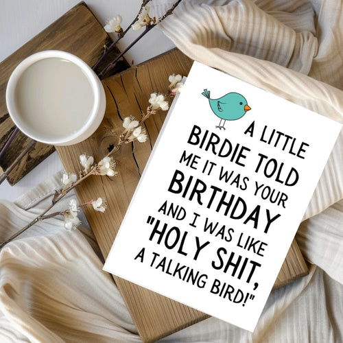 White rectangular card with a teal cartoon bird, reading “A little birdie told me it was your birthday and I was like ‘Holy shit, a talking bird!’”