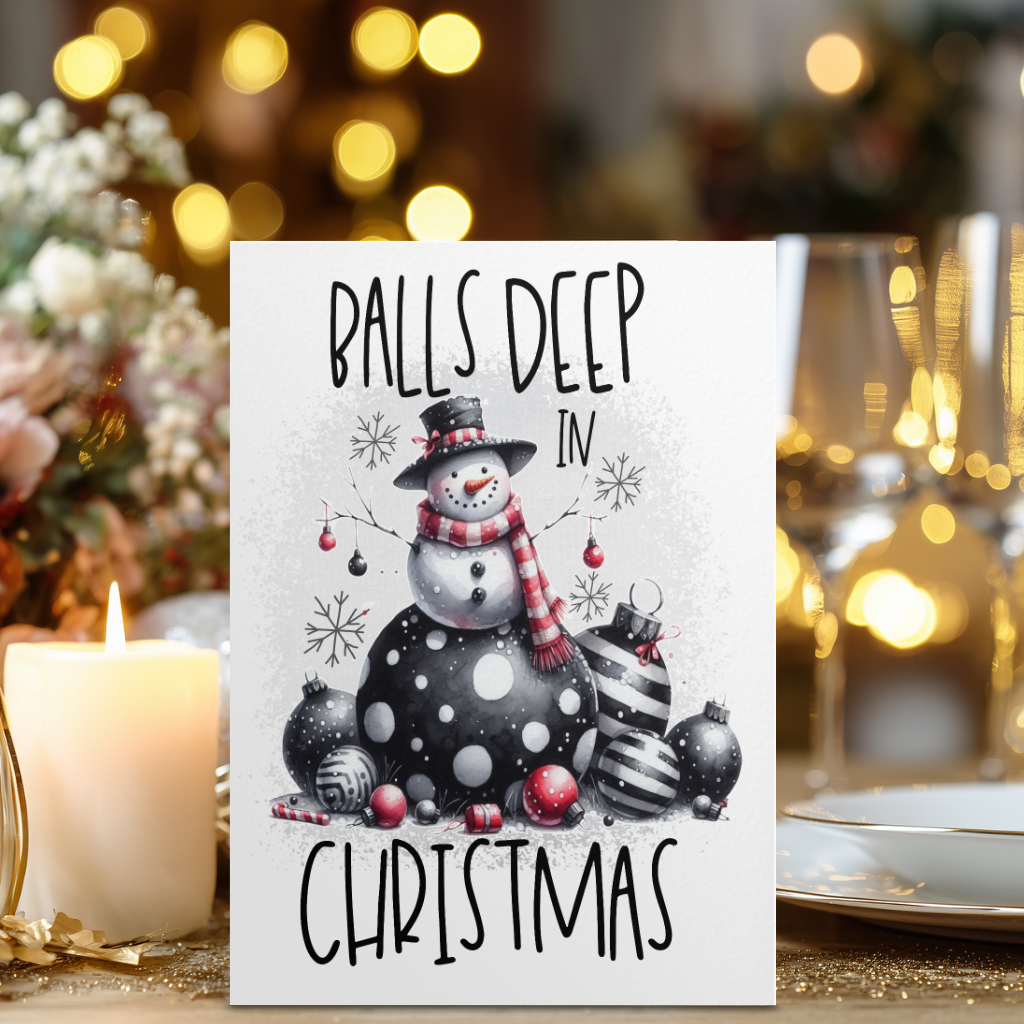 White rectangular Christmas card with a snowman wearing a black top hat and red striped scarf among baubles, reading “Balls Deep in Christmas.”