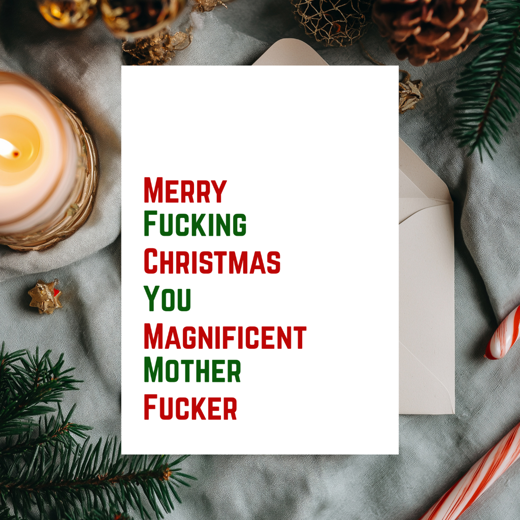 A white Christmas greeting card with bold red and green text reading 'Merry Fucking Christmas You Magnificent Mother Fucker', styled on a gray fabric surface with a white envelope, candle, pine branches, and holiday decor.